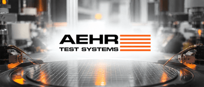 Aehr Test Systems logo displayed over a semiconductor wafer with test probes in a manufacturing facility.