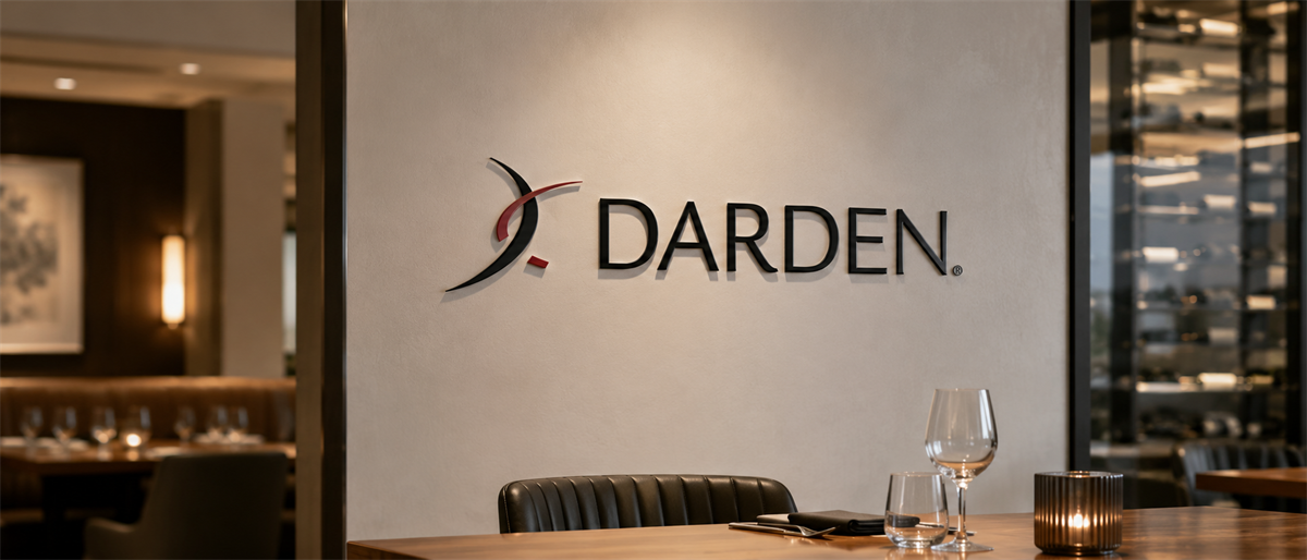 Darden Restaurants logo displayed on a wall above a dining table with wine glasses in a restaurant setting.