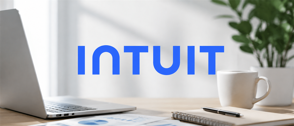 Intuit logo displayed over a desk with a laptop, coffee mug, notebook, plant, and financial chart printout.