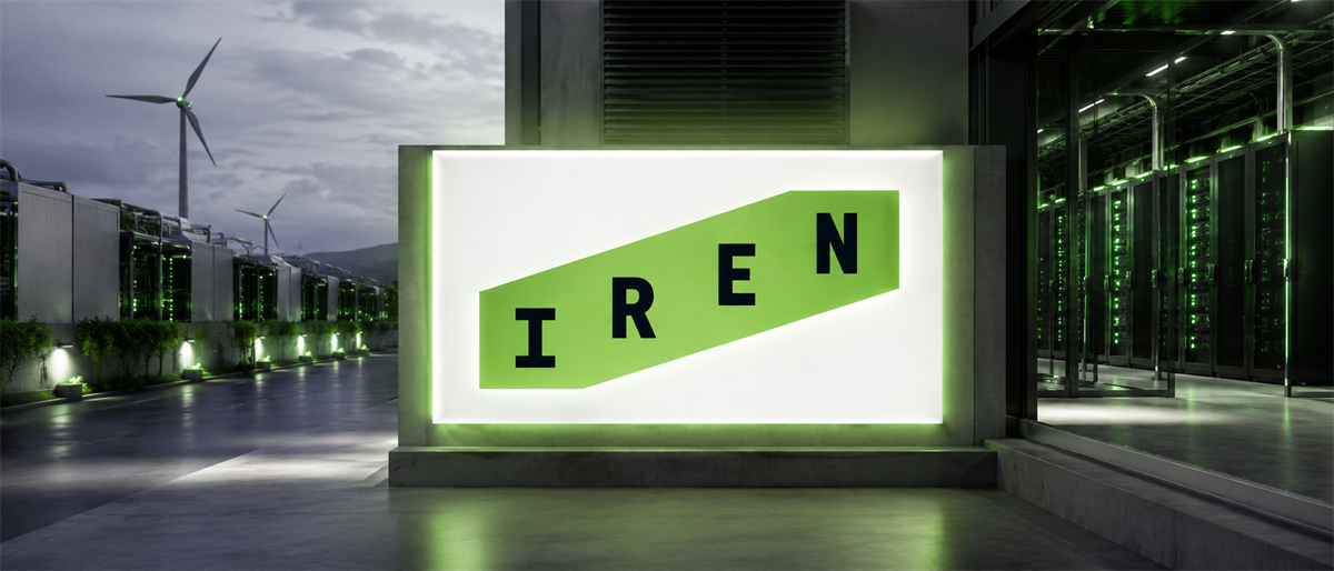Illuminated IREN logo sign outside a data center building at night, with wind turbines and server racks visible.