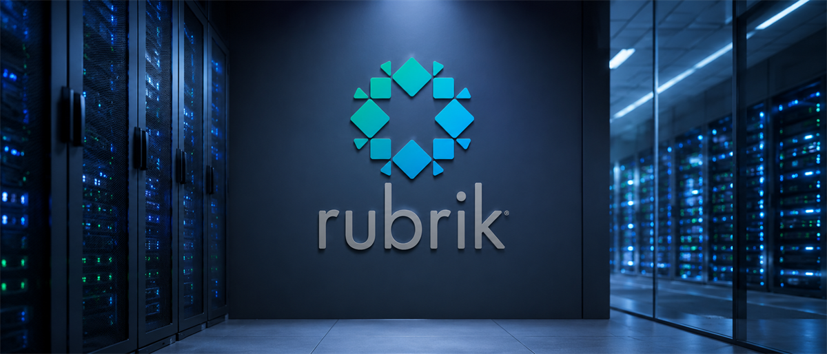 Rubrik logo displayed on a wall in a data center hallway lined with illuminated server racks.