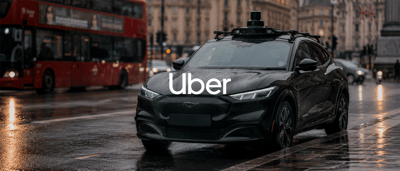 A black autonomous vehicle with rooftop sensors displays the Uber logo on a rainy city street.