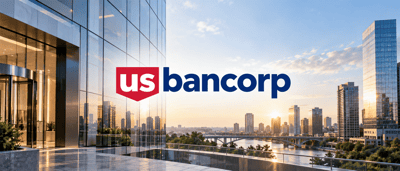 U.S. Bancorp logo displayed over a glass office building with a city skyline and river in the background.