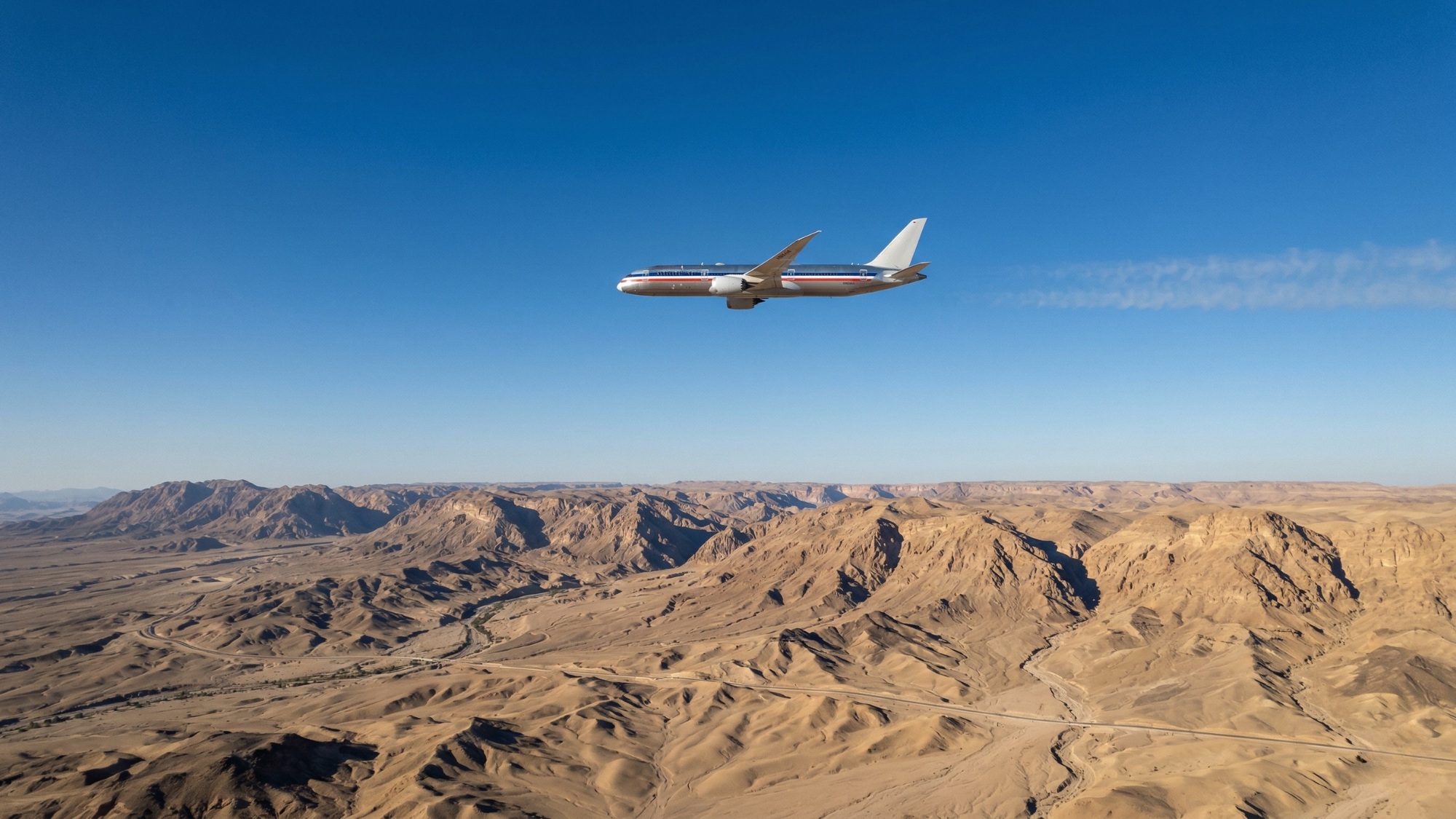 Commercial passenger jet flying over a vast desert landscape, illustrating airline industry impact from rising fuel costs.