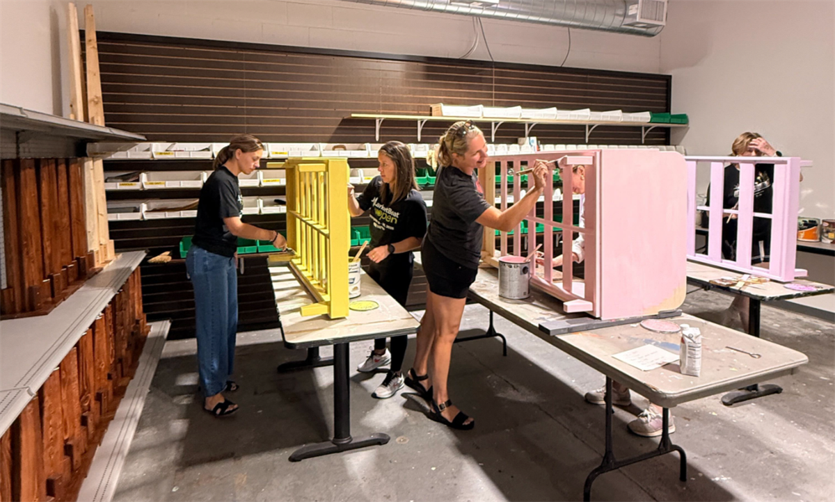 MarketBeat employees paint children’s beds at the Furniture Mission.