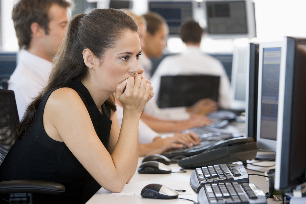 Day trading risk management: Image of a woman sitting at a computer terminal weighing the risks of trading