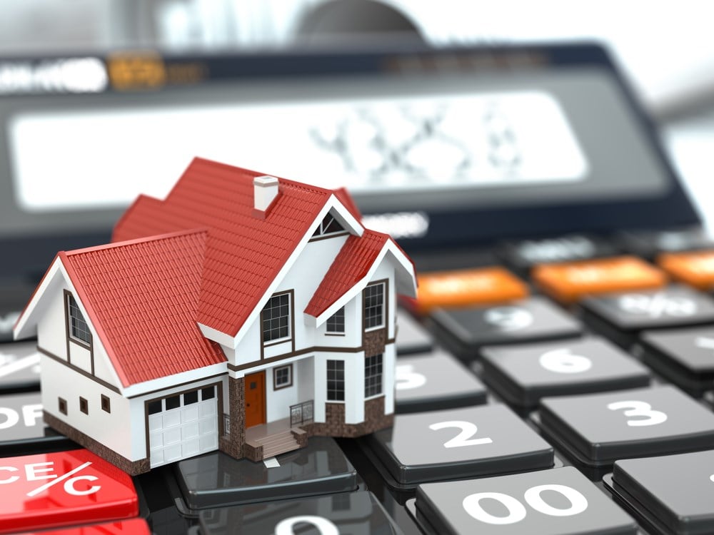 how to start investing in real estate: Image of a small house on a calculator