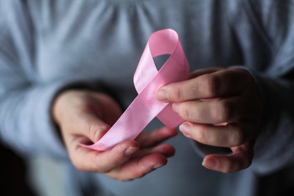 Cancer stocks to consider; image of someone holding a pink ribbon
