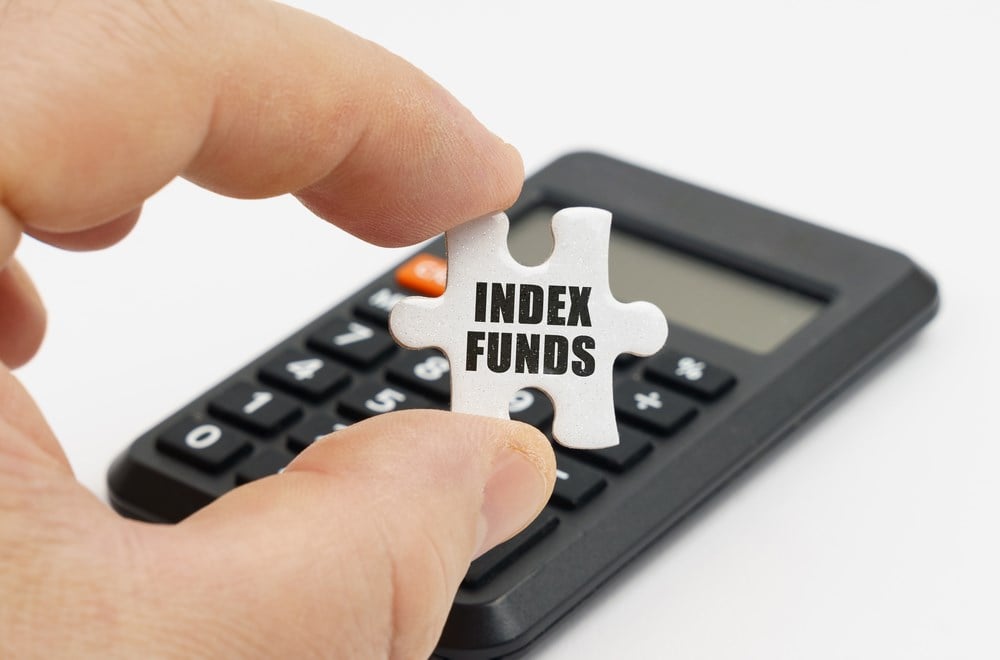 What is an index fund and how does it work? Man holding puzzle piece by calculator