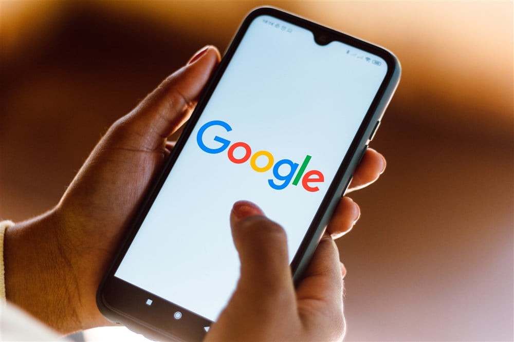 Google logo on smartphone with hands