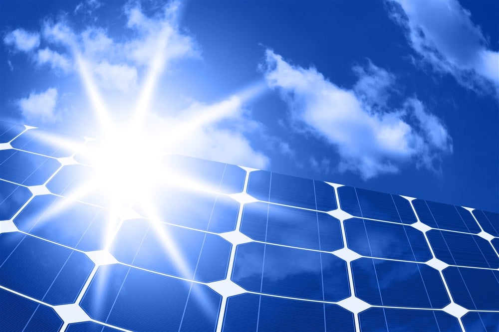 array of solar panels with sunbeam and blue skies