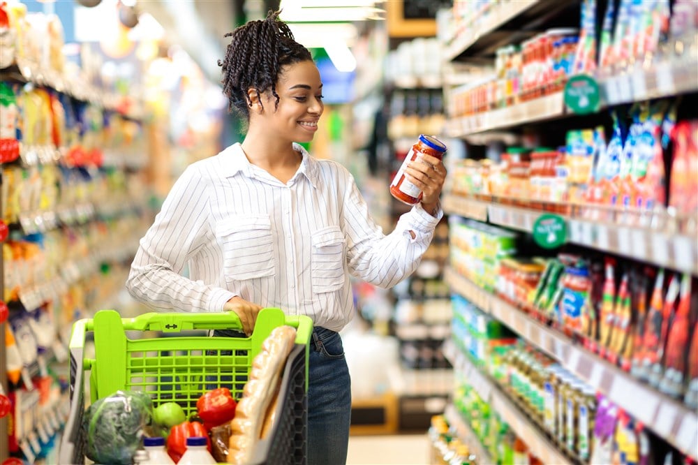woman shopping in grocery store with green basket