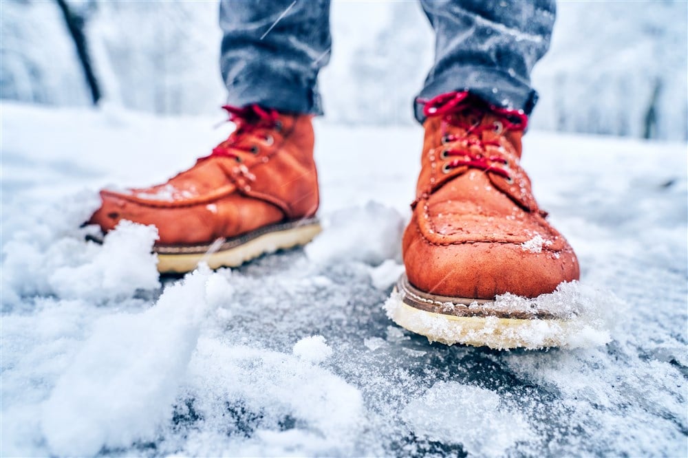 feet of a man in brown boots on wet winter pavement