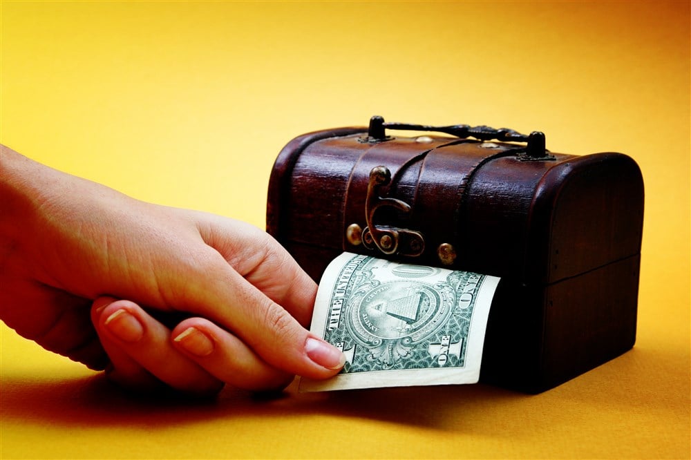 wooden cashbox with dollar bill partly exposed on yellow