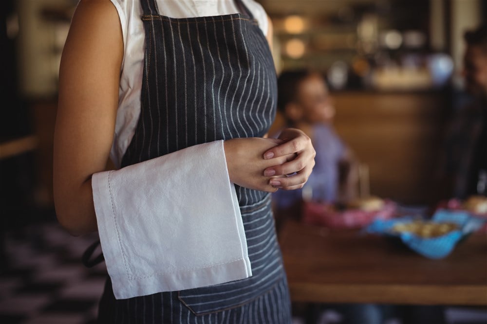 close-up image of server with pinstripe apron and white napkin