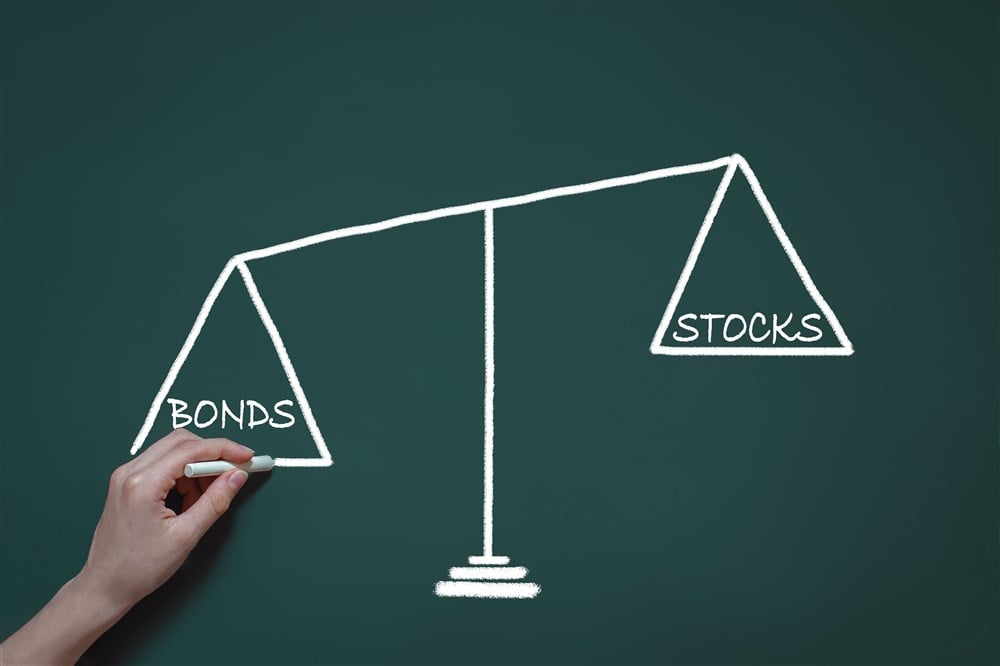 chalk drawing showing a scale with words stocks and bonds indicating balanced portfolio