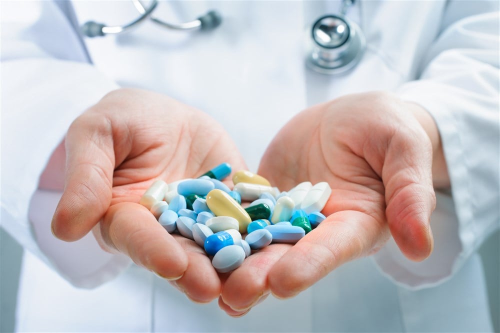 closeup of hands holding variety of pills