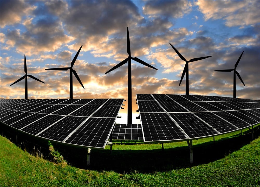 photo of solar panel arrays with wind turbines at sunrise