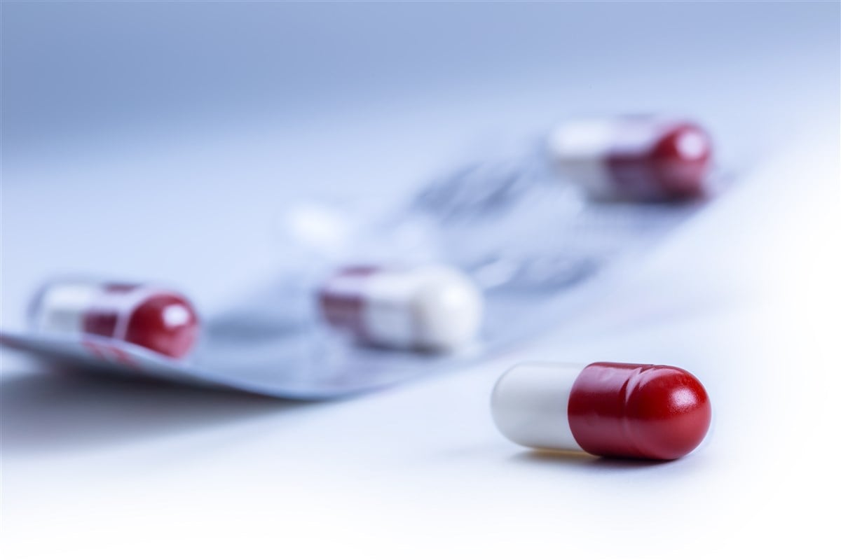 Close-up image of generic red and white capsules on blue background