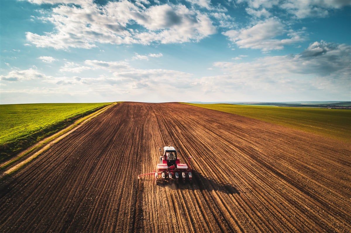 Farmer in tractor preparing farmland with seedbed for the next year; learn how to invest in farmland