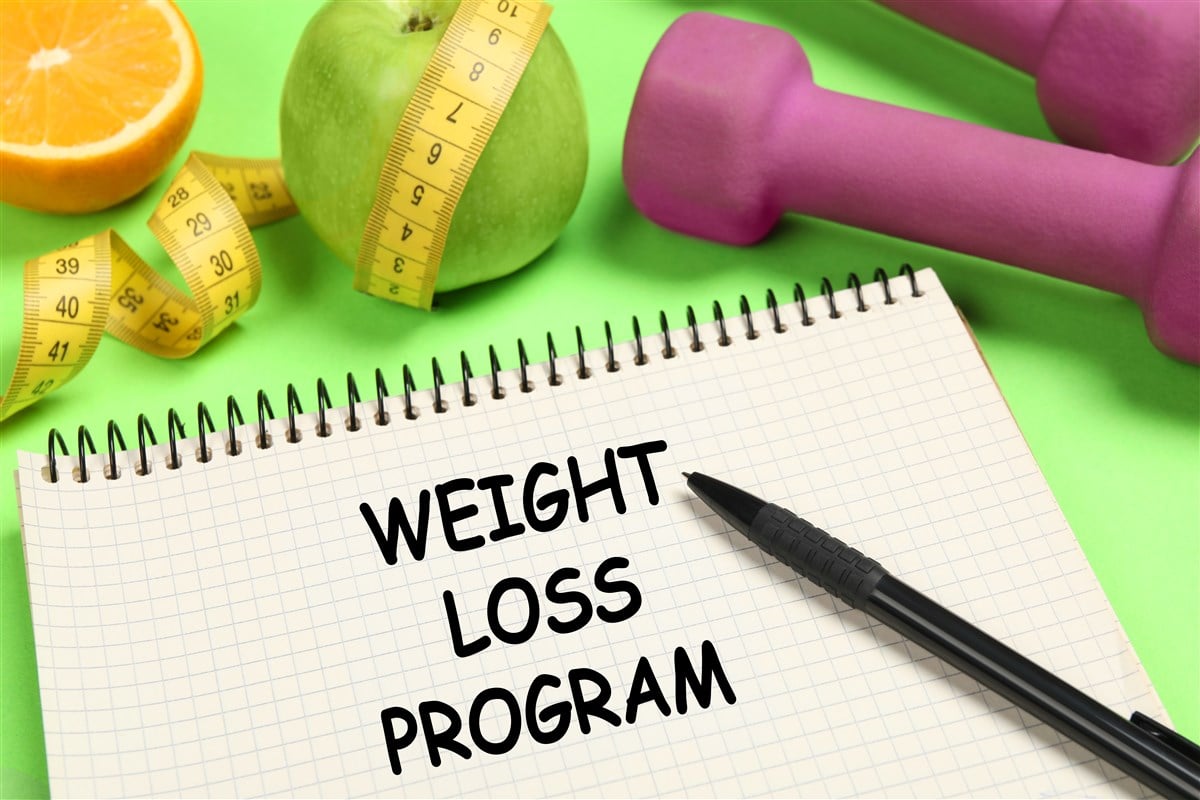 photo of notebook with words weight loss program with fruity, dumb bells, and tape measure 
