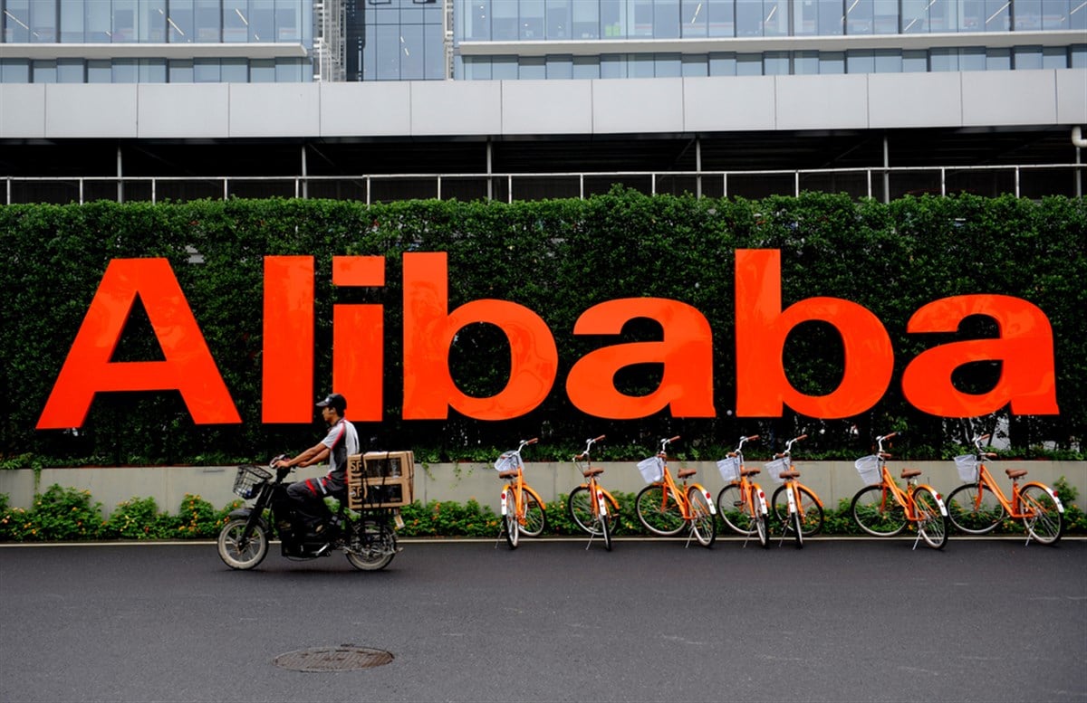 Alibaba logo behind bicycles and deliveryman on a bike; learn more about Alibaba stock