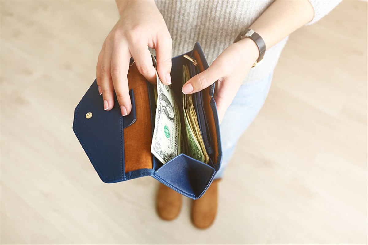 Girl with blue wallet full of money learning how to buy stock