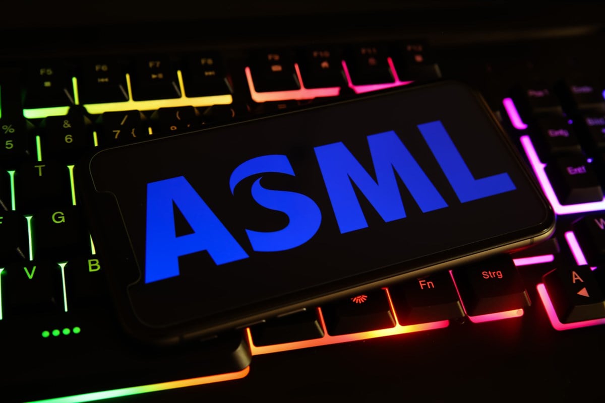Closeup of mobile phone screen with logo lettering of asml holding on computer keyboard