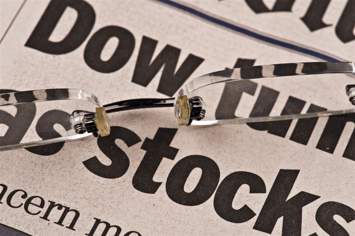 photo of newspaper with words Dow Stocks prominently displayed;glasses resting on paper