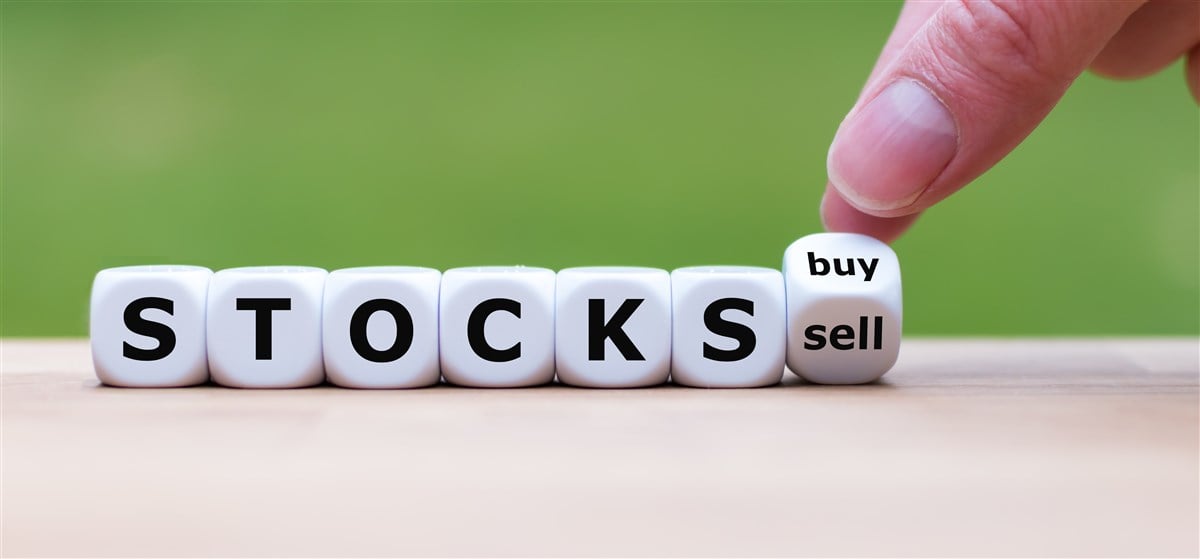 Photo of hand turning a dice and changes the word "sell" to "buy".