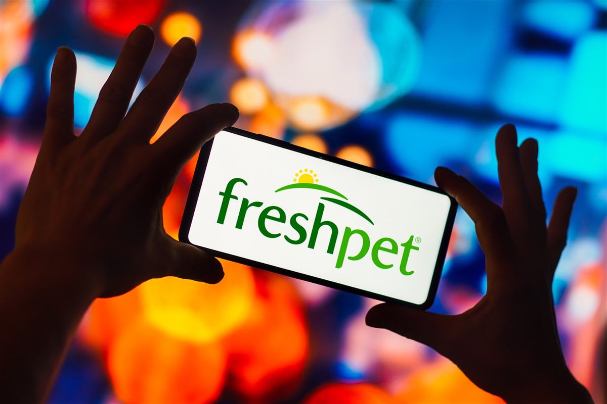Hands holding mobile device with freshpet logo on the screen