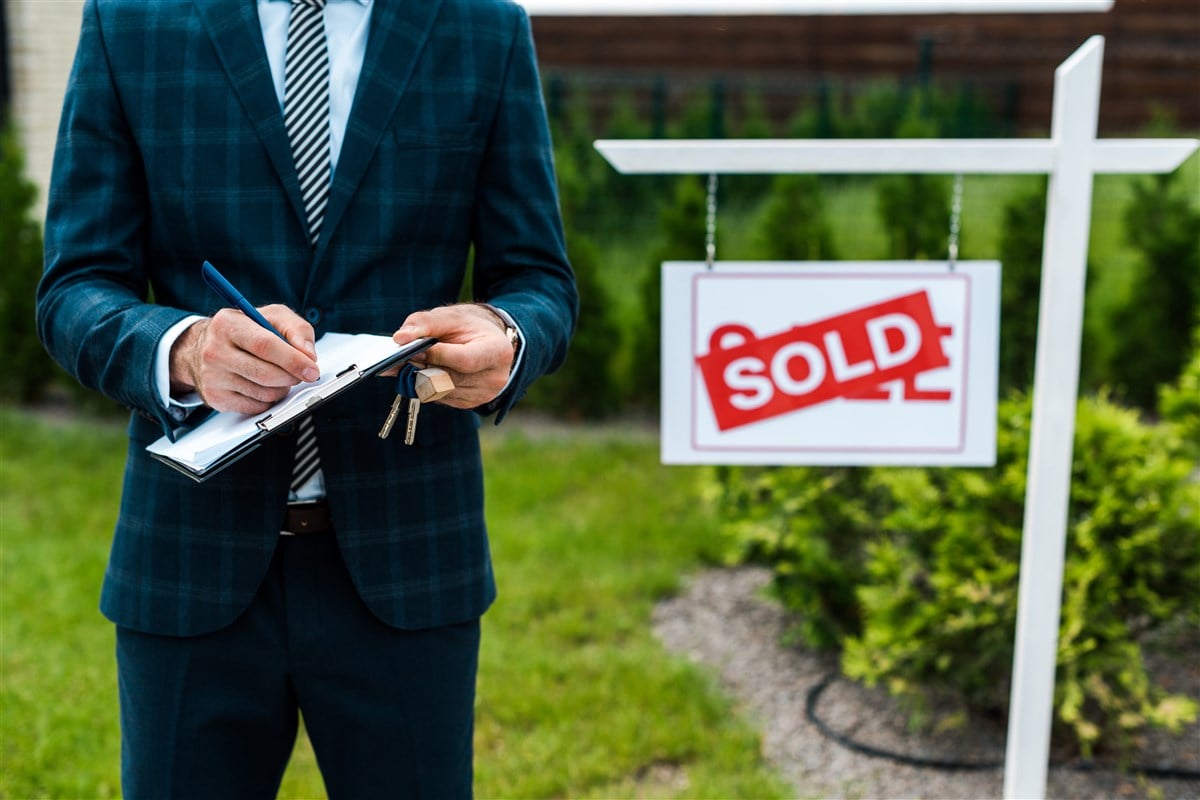 picture of realtor in front of house that has been sold