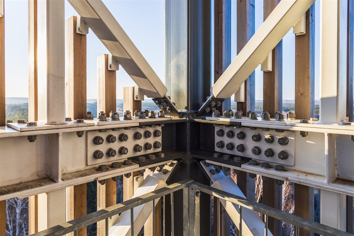 Close up photo of steel screw bolts connecting a massive steel industrial structure.  Will Simpson Manufacturing be the future dividend king?