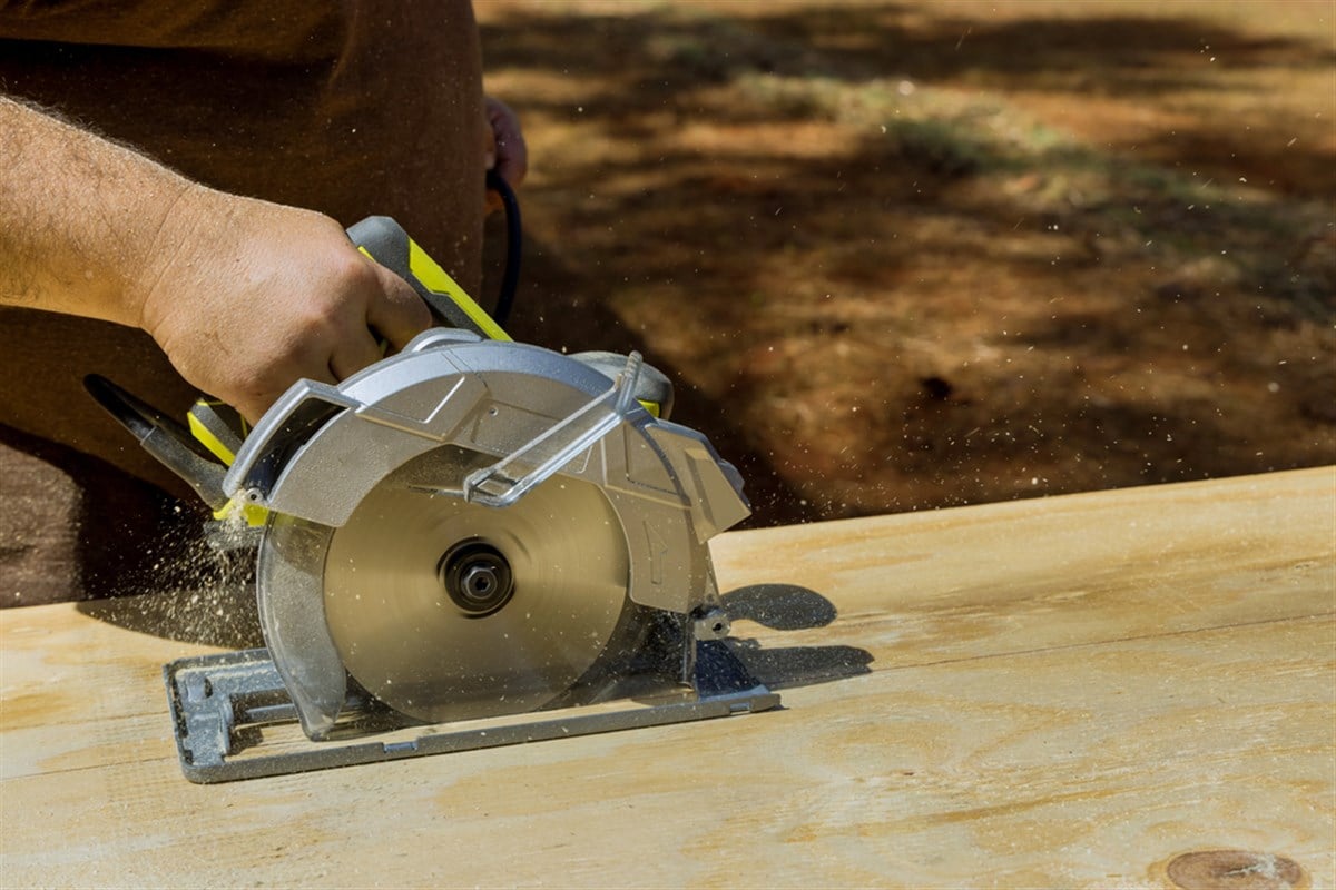 Cutting plywood with a circular saw that is held in the hand by worker