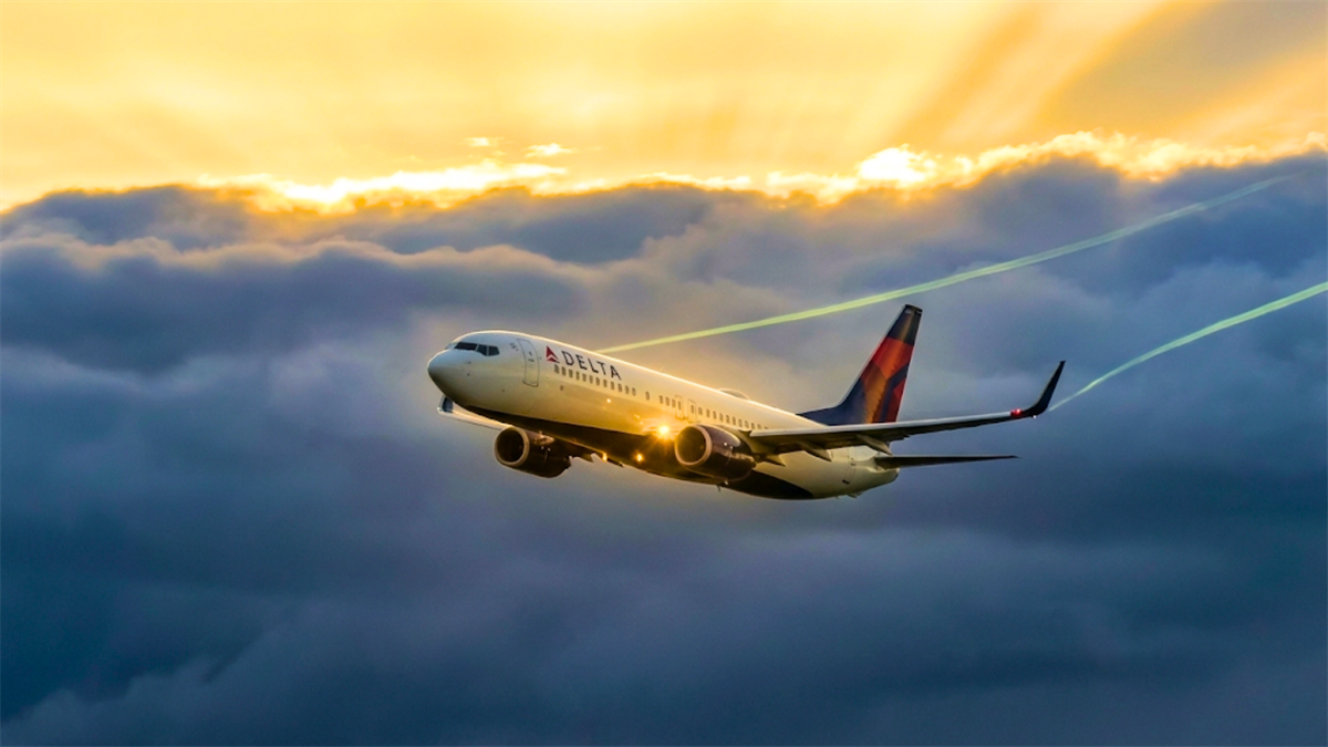 Delta Air Lines jet flying above storm clouds, symbolizing resilience and forward momentum amid challenging conditions.