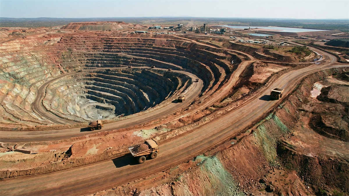 Open-pit copper mine with haul trucks on spiral roads, symbolizing 2026 supply squeeze and AI-driven demand.