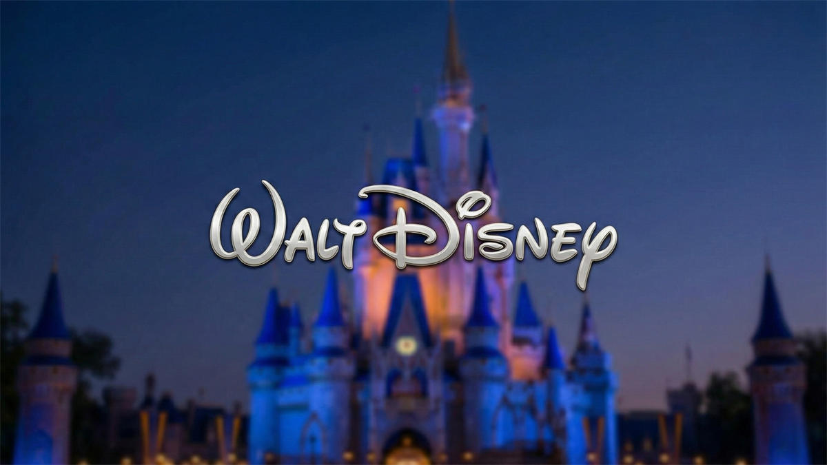 Walt Disney logo over a lit theme-park castle at dusk, symbolizing Disney’s entertainment business.