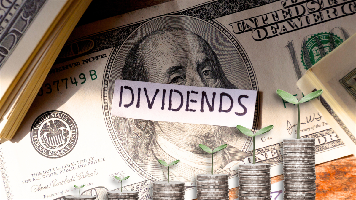 Stacks of coins with small plants and a "Dividends" label rest on US hundred-dollar bills.