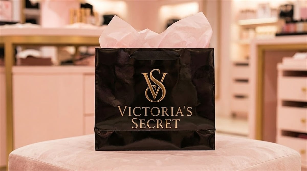 A Victoria's Secret branded black shopping bag with tissue paper sits inside a retail store.