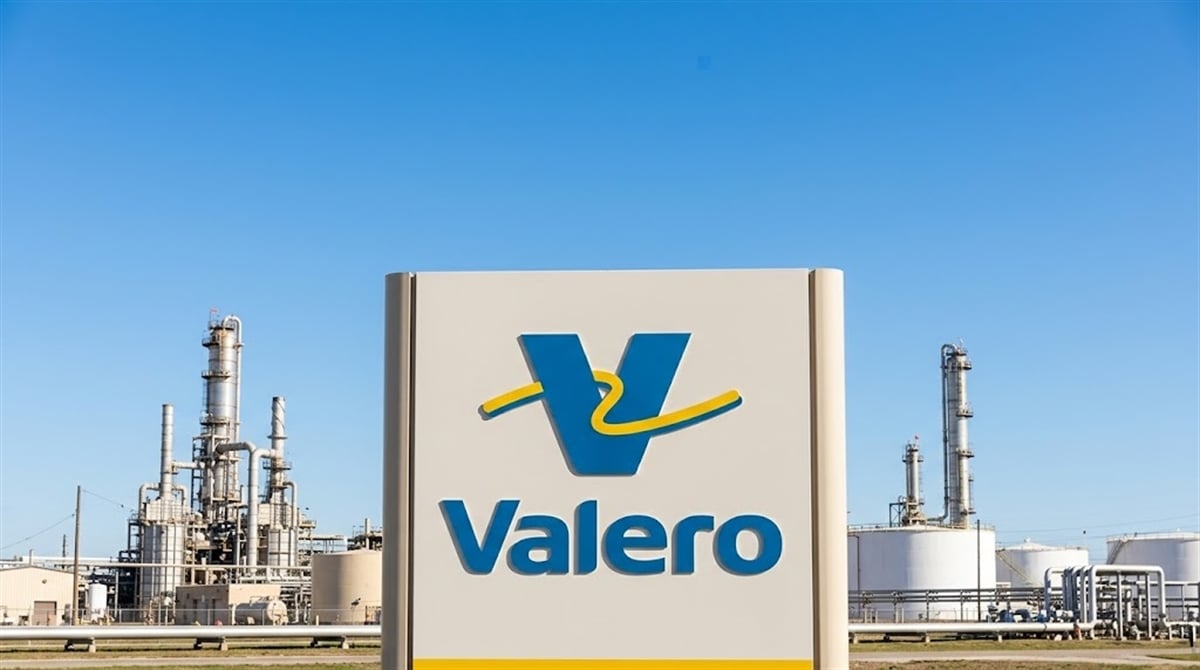 Valero Energy logo sign displayed in front of a petroleum refinery under a clear blue sky.