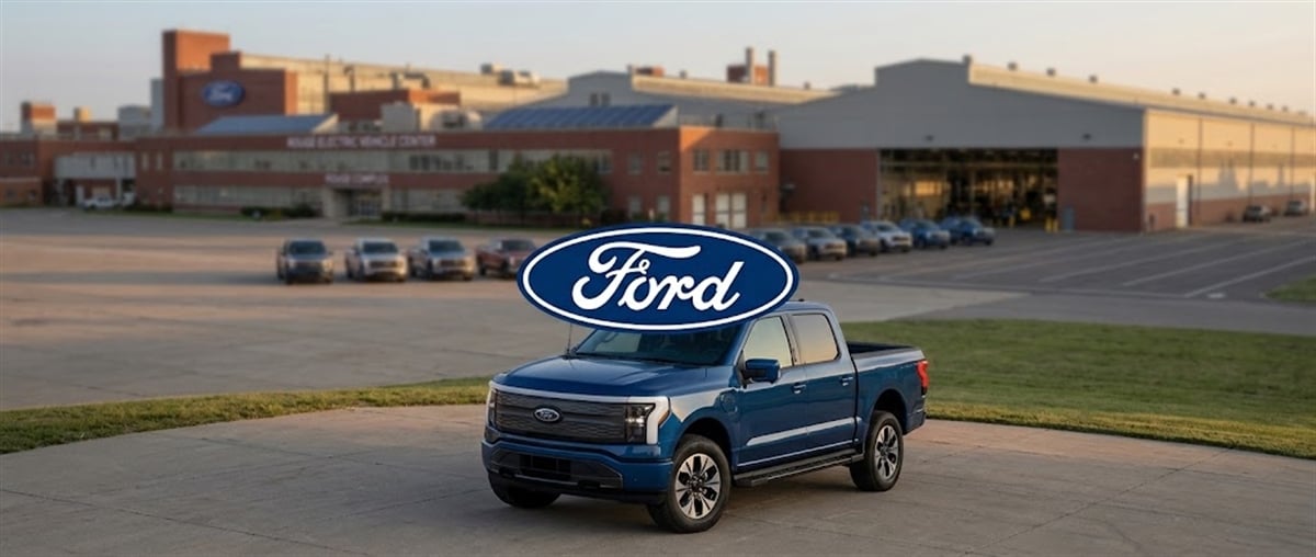 Ford logo and a blue F-150 Lightning pickup truck parked outside the Rouge Electric Vehicle Center.