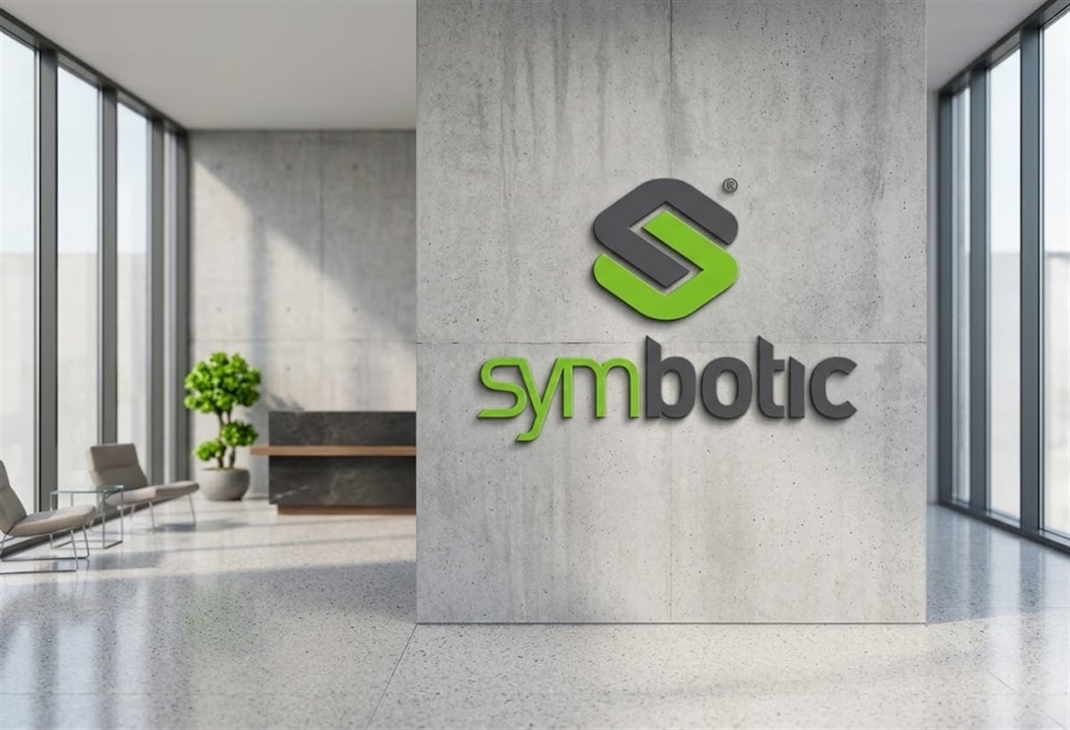 Symbotic logo displayed on a concrete wall in a modern office lobby with seating and large windows.