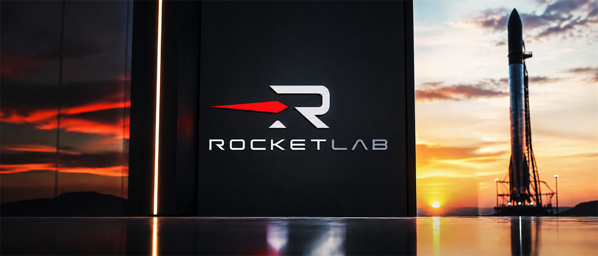 Rocket Lab logo displayed on a sign with a rocket on a launch pad at sunset in the background.