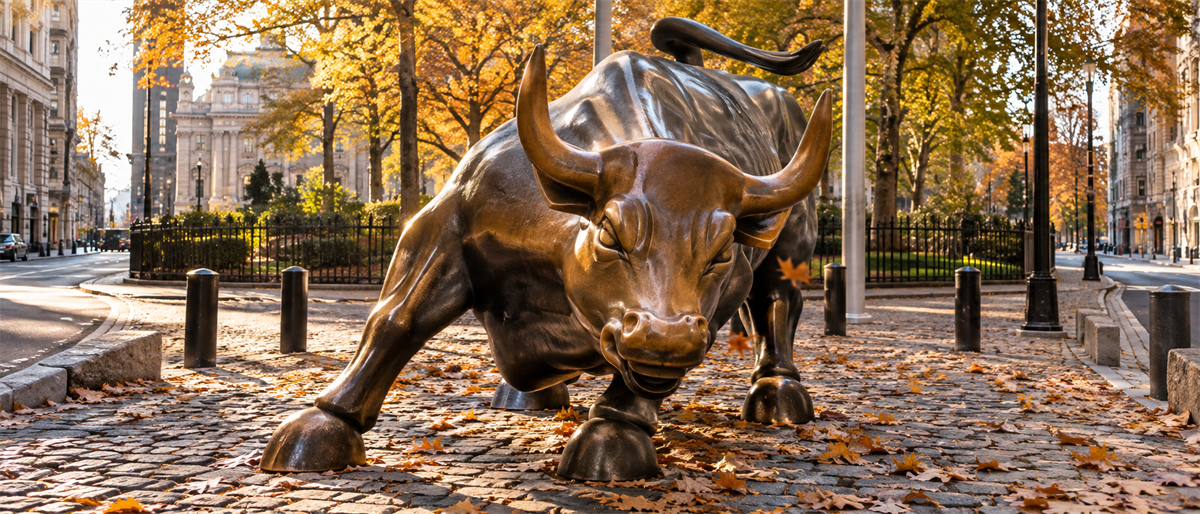 The Charging Bull bronze statue near Wall Street, surrounded by fallen autumn leaves and city buildings.