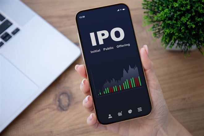 female hands hold phone with IPO stocks purchase app on screen at table in office 