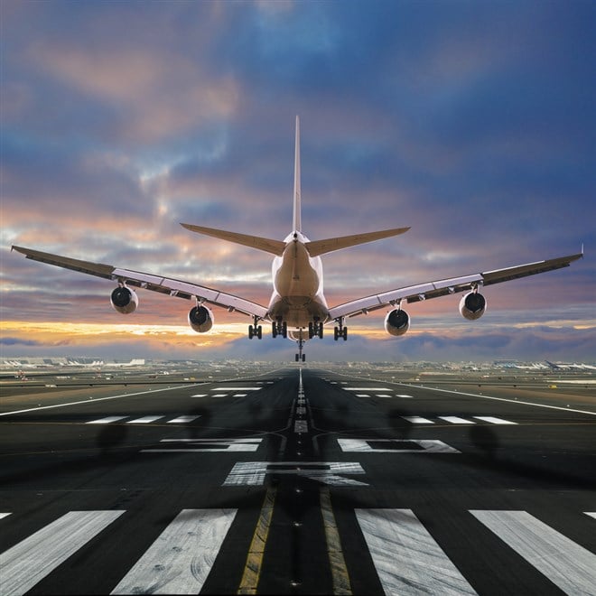 Airplane landing at the airport, back view. Learn about how to invest in the best airline ETFs.