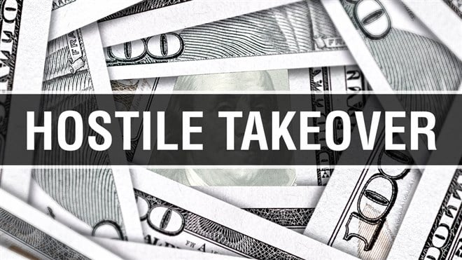 Hostile takeover image with money: What is a hostile takeover? Learn more.