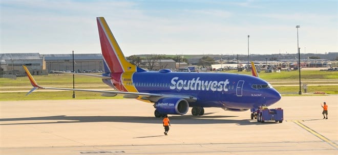 Southwest Airlines Boeing 737 passenger jet being pushed back from the airport terminal by a small tractor for take off.