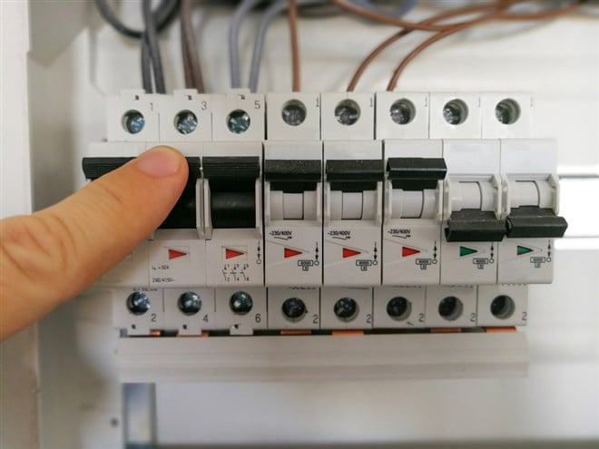 Male finger switching circuit breakers inside electrical panel cabinet; what is a circuit breaker in the stock market?
