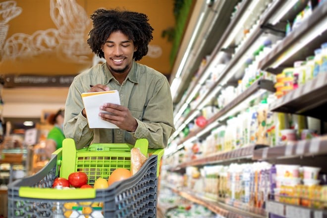 Cheerful guy searching for consumer staples in a supermarket